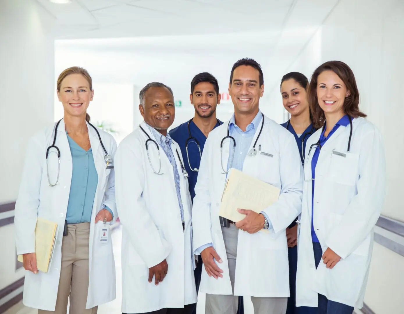 Group of smiling doctors in hospital corridor.