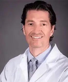 Man in white lab coat smiling.