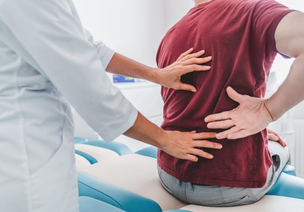 Doctor examining a patient's lower back for pain or injury.