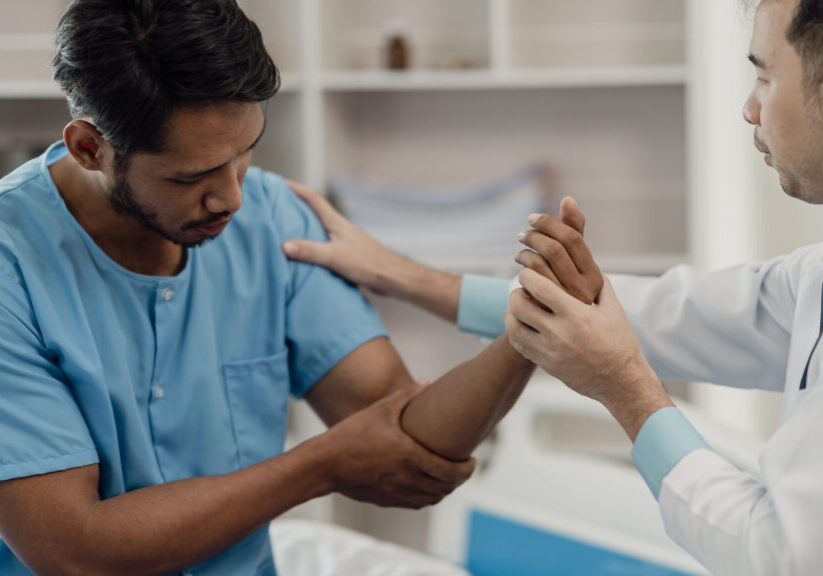 A doctor examining a patient's wrist in a clinical setting.