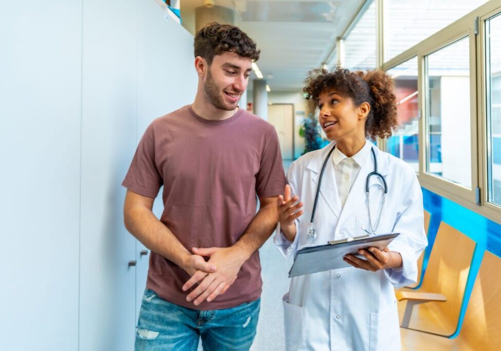 A doctor and patient walking together in a hospital corridor.